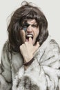 Portrait of young man in fur coat with finger in mouth against gray background Royalty Free Stock Photo