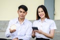 Portrait of young man and girl in university uniform sitting and hold a small house and calculator, Concept of sustaining a house