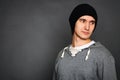 Portrait of a young man in a gray hoodie and a black hat. Posing on a gray background Royalty Free Stock Photo