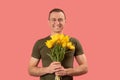 Portrait of young man holding bouquet of yellow tulip flowers and smiling isolated on pink background. Copy space Royalty Free Stock Photo