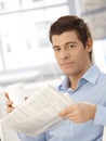 Portrait of young man holding coffee and newspaper Royalty Free Stock Photo