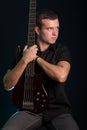Portrait of young man holding electric bass guitar