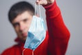 Portrait of young man holding medical protective mask on studio background, boy take off flu mask, concept of personal Royalty Free Stock Photo