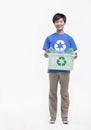 Portrait of young man holding recycling bin and wearing a recycling symbol t-shirt, studio shot Royalty Free Stock Photo
