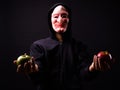 Portrait of young man with hoodie and horror mask holding apples