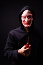 Portrait of young man with hoodie and horror mask holding scissors