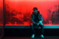 Portrait of a young man in a hoodie sitting on a bench in a room with neon light Royalty Free Stock Photo