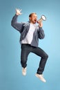 Portrait of young man jumping of joy shouting to loudspeaker isolated blue studio background. Irritated young guy in Royalty Free Stock Photo