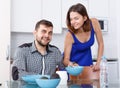 Young man at kitchen table and woman preparing breakfast Royalty Free Stock Photo