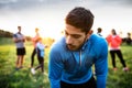 A portrait of young man with large group of people doing exercise in nature. Royalty Free Stock Photo