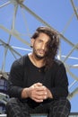 Young man latin acrobatic street dancer with long hair sitting in a skate park Royalty Free Stock Photo