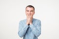 Portrait of young man laughing and covering his mouth with hand over white background. Royalty Free Stock Photo