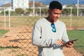 Portrait of a young man leaning on a fence, holding a digital tablet