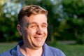 Portrait of a young man on nature background. Emotion facial expression. Smug smile, feelings and people reaction.