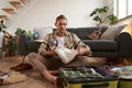 Portrait of young man picking clothes for holiday, sitting on floor with suitcase, packing on vacation, going on a Royalty Free Stock Photo