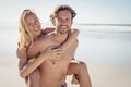 Portrait of young man piggybacking beautiful woman at beach Royalty Free Stock Photo