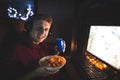 Portrait of a young man playing a gamer sitting in a headset with a can of cola in hands and a plate