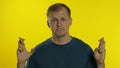 Portrait of young man posing in t-shirt. Handsome guy crossed his fingers, prays, wished good luck Royalty Free Stock Photo