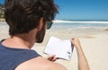 Portrait of a young man reading book at the beach Royalty Free Stock Photo
