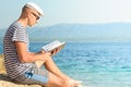 Portrait of a young man reading book on the beach Royalty Free Stock Photo