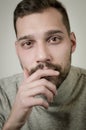 Portrait of a young man with a short beard in a moment of reflection with his hand to his chin Royalty Free Stock Photo