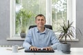 Portrait of young man sitting behind his workplace in cabinet. Office Manager. Office worker. Friendly director at the table Royalty Free Stock Photo