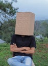 Portrait of a young man sitting with a cardboard box on his head Royalty Free Stock Photo