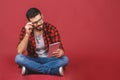 Portrait of young man sitting on the floor using a tablet pc, isolated against red background. Ready for your design Royalty Free Stock Photo