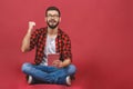 Portrait of young man sitting on the floor using a tablet pc, isolated against red background. Ready for your design Royalty Free Stock Photo