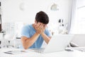 Portrait of young man sitting at his desk at home with a laptop sad covering his face with his hands. Freelance and selfemployment Royalty Free Stock Photo