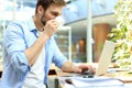 Portrait of young man sitting at his desk in the office, drinking coffee and typing on the laptop Royalty Free Stock Photo