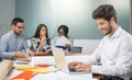 Portrait of young man sitting at his desk and working on laptop in the office. Royalty Free Stock Photo