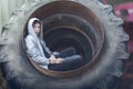 Young man sitting in a huge wheel of a tractor Royalty Free Stock Photo