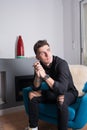 Portrait of a young man sitting in a living room near the fireplace. Dressed in black, looking to his left near the window Royalty Free Stock Photo