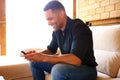 Young man sitting on sofa and using mobile phone at home Royalty Free Stock Photo