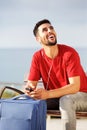 Young man smiling with suitcase and mobile phone Royalty Free Stock Photo