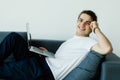 Portrait of young man smiling and using laptop while sitting on sofa at home Royalty Free Stock Photo