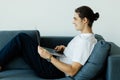 Portrait of young man smiling and using laptop while sitting on sofa at home Royalty Free Stock Photo