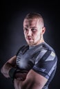 Portrait of a young man in sport outfit in fitness studio against dark background