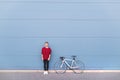 Portrait of a young man standing with a bike on a pastel blue background and looking into the camera Royalty Free Stock Photo