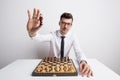 Portrait of a young man in a studio, playing chess and holding a king chessman.