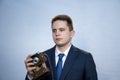 Portrait of a young man in a suit with an old camera, perhaps he is a novice journalist doing a report, a diplomat or secret