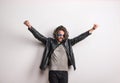 Portrait of a young man with sunglasses and leather jacket in a studio, arms stretched. Royalty Free Stock Photo