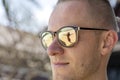 Portrait of a young man in sunglasses in which the silhouette of a girl is reflected on the tropical beach near sea Royalty Free Stock Photo