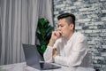 Portrait of young man thinking while serious working  at home with laptop on desk Royalty Free Stock Photo