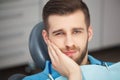 Portrait of young man with tooth pain sitting in a dentist's cha