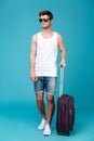 Portrait of a young man tourist in sunglasses with suitcase Royalty Free Stock Photo