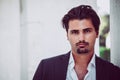 Portrait of young man with trendy style. Trendy hair and goatee. He wears a white shirt and jacket Royalty Free Stock Photo