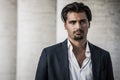 Portrait of young man with trendy style. Trendy hair and goatee. He wears a white shirt and jacket