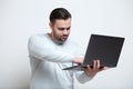 Portrait of young man typing on laptop keyboard over white background